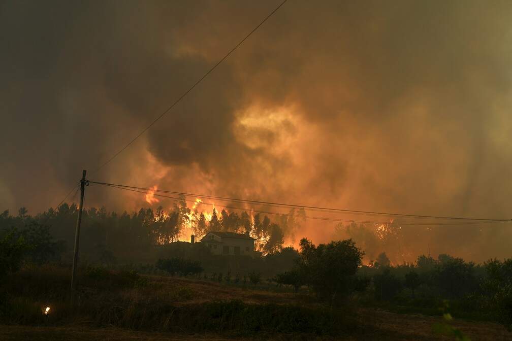 Incêndio florestal atinge uma casa na aldeia de Bemposta, perto de Ansião, no centro de Portugal, na quarta-feira (13). Milhares de bombeiros continuam a combater incêndios em todo o país, que forçaram a saída de dezenas de pessoas das suas casas. — Foto: Armando Franca/AP